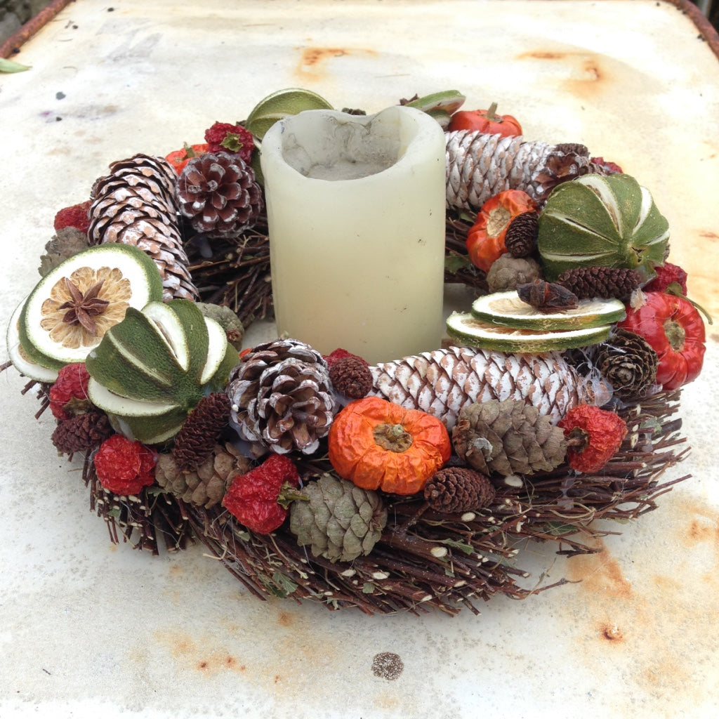 Christmas door wreath decorated with green limes and red peppers, white fir cones on a natural willow base.