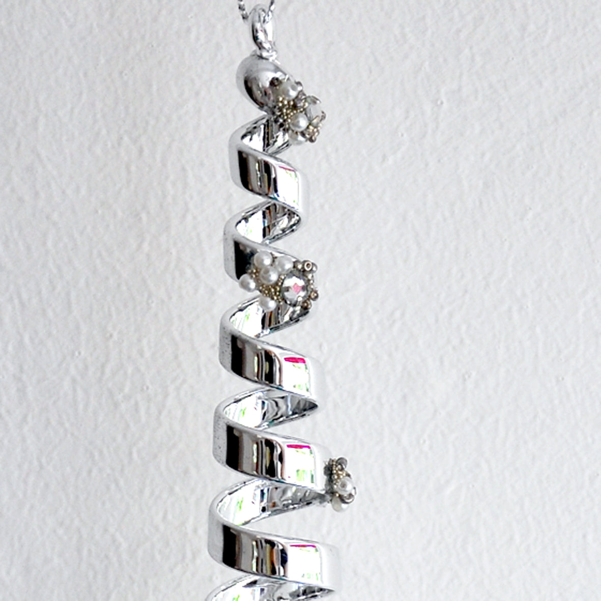 This striking silver spiral is made from glass and decorated with diamonte, beads and pearls.