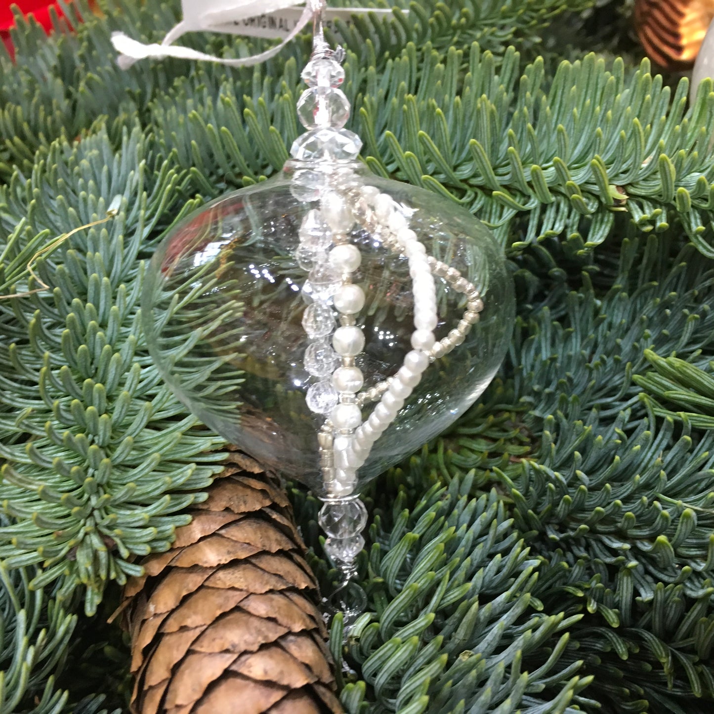 Delicate small clear glass decoration with strings of clear and pearl beads inside which catch the light.