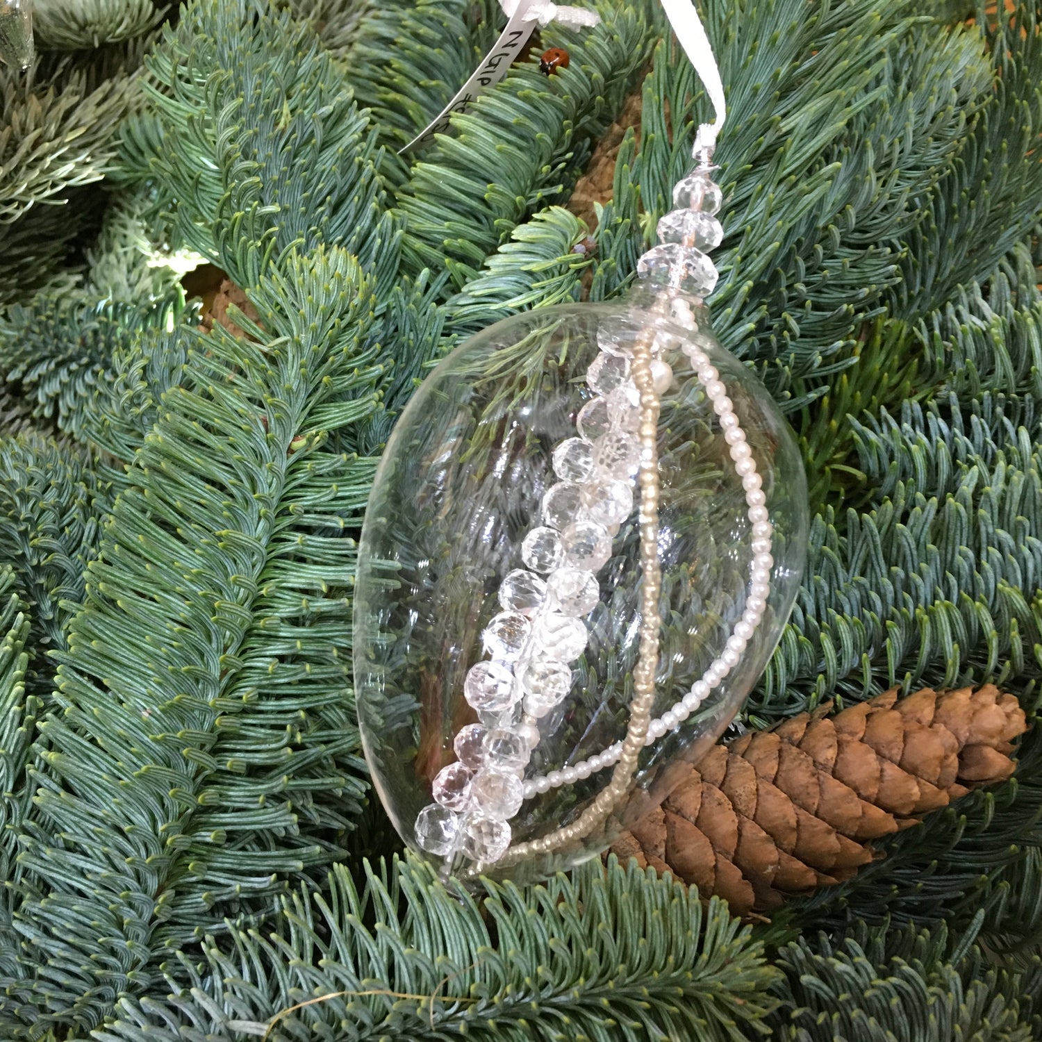 Clear egg-shaped decoration with strings of pearl, silver and glass beads that sparkle in the light