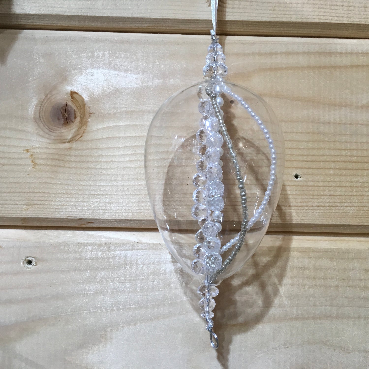 Clear egg-shaped decoration with strings of pearl, silver and glass beads that sparkle in the light