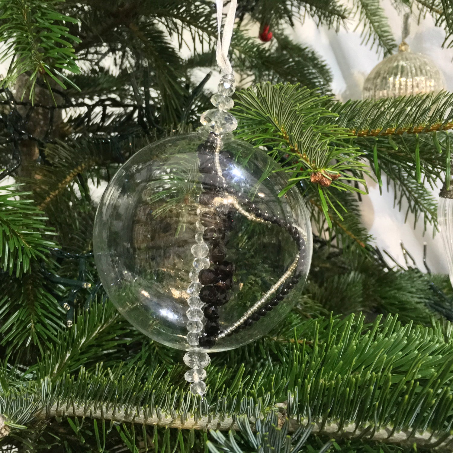 Flat clear glass decoration filled with sparkling black, silver and clear beads