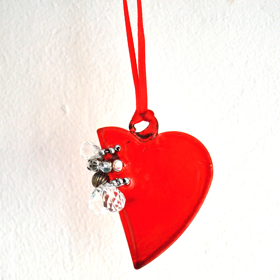 This bright red love heart shaped ornament is made from glass and decorated with beads.