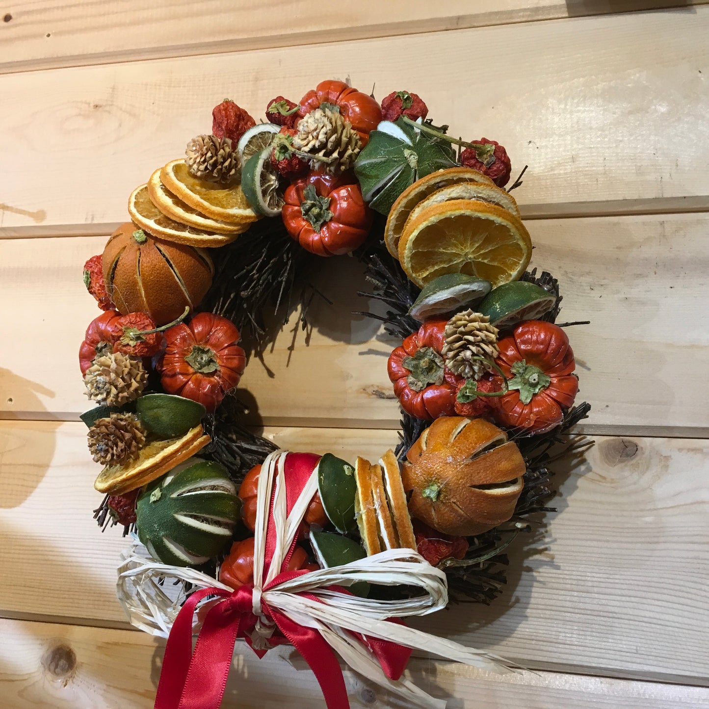 Circle shaped twig wreath that has been beautifully decorated with an assortment of dried fruits, cinnamon sticks and pine cones, and scented with a wonderful Christmas fragrance. With an additional decorative red bow and hanger.
