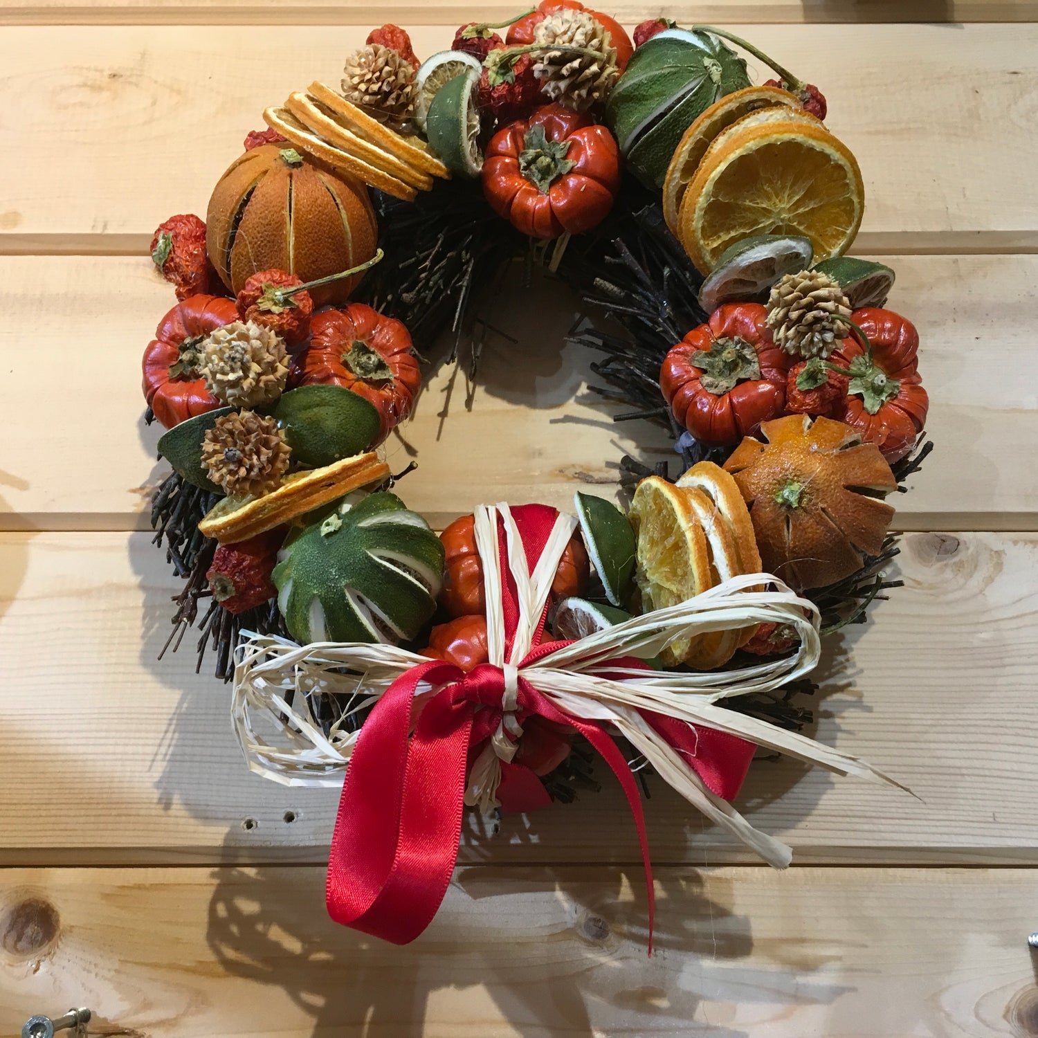 Circle shaped twig wreath that has been beautifully decorated with an assortment of dried fruits, cinnamon sticks and pine cones, and scented with a wonderful Christmas fragrance. With an additional decorative red bow and hanger.