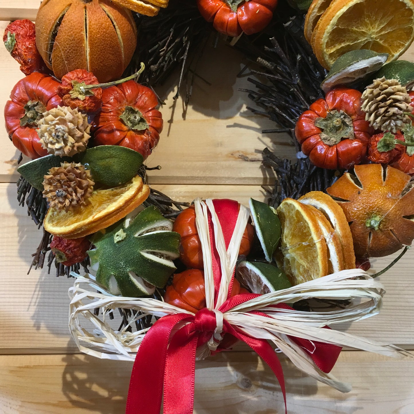 Circle shaped twig wreath that has been beautifully decorated with an assortment of dried fruits, cinnamon sticks and pine cones, and scented with a wonderful Christmas fragrance. With an additional decorative red bow and hanger.