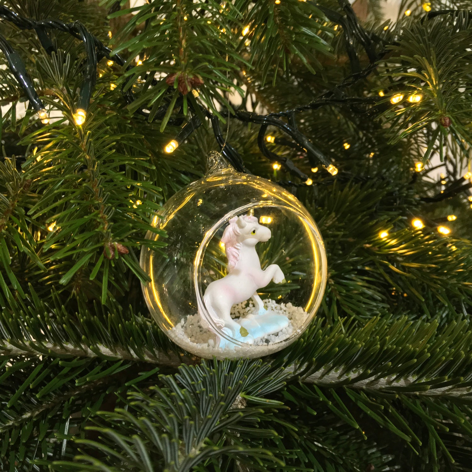 A beautiful open glass bauble Christmas tree decoration, with a glittery unicorn inside.