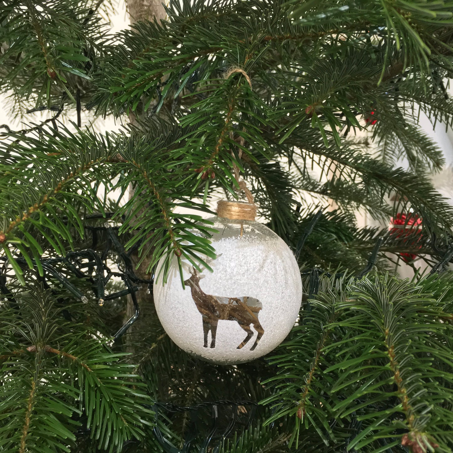 Lovely cut out deer in a glass bauble filled with pieces of wood and hung with rustic string.