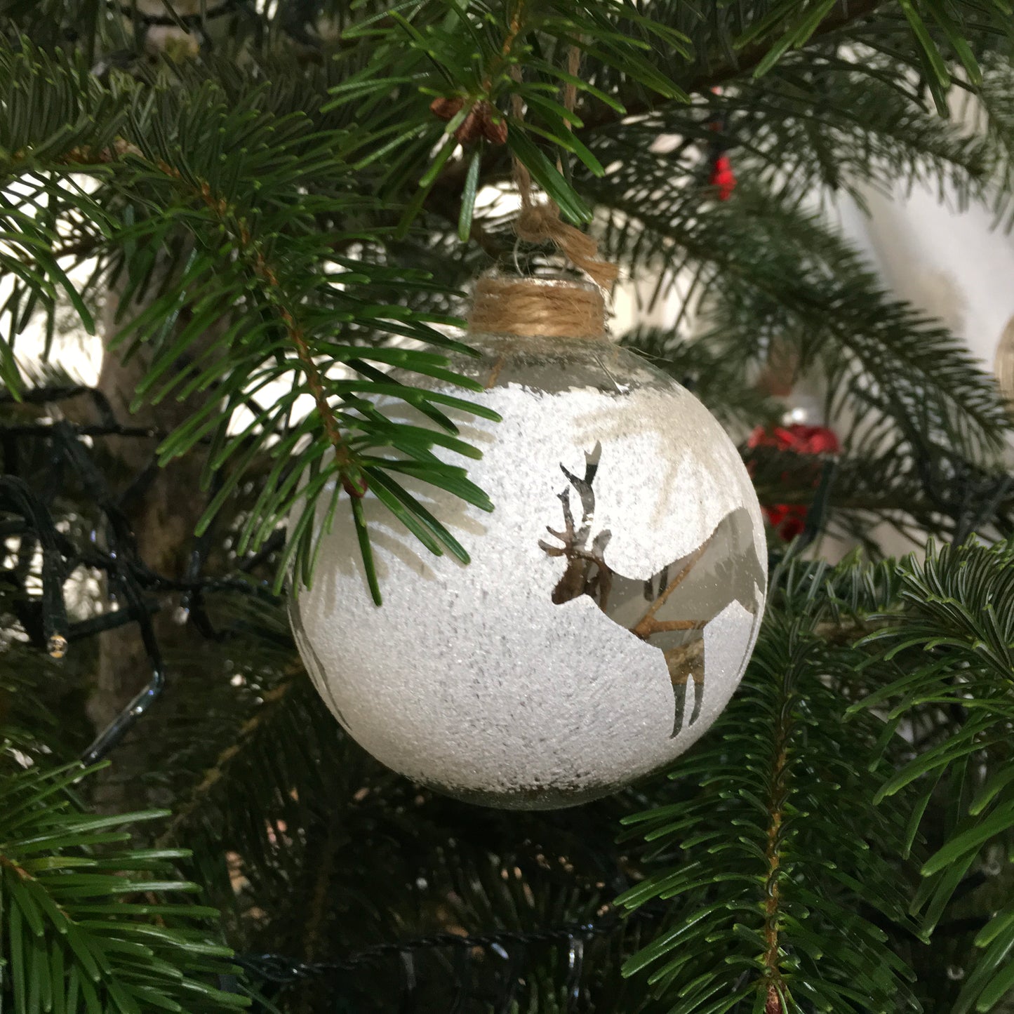 Lovely cut out deer in a glass bauble filled with pieces of wood and hung with rustic string.
