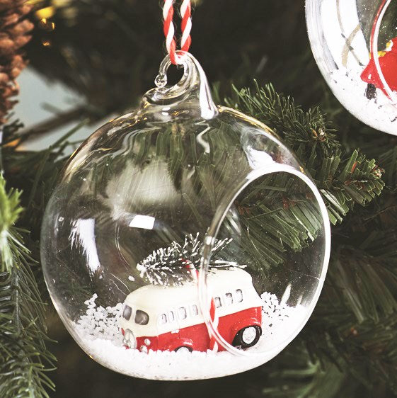 Open glass bauble with a red and white campervan carrying a Christmas tree in the snow.