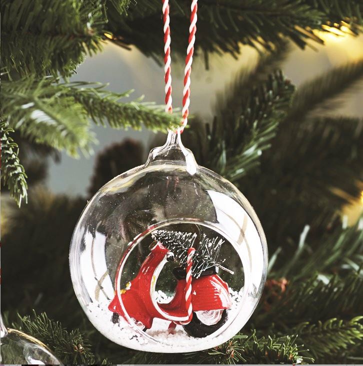 Open glass bauble with a red and white scooter carrying a Christmas tree in the snow.