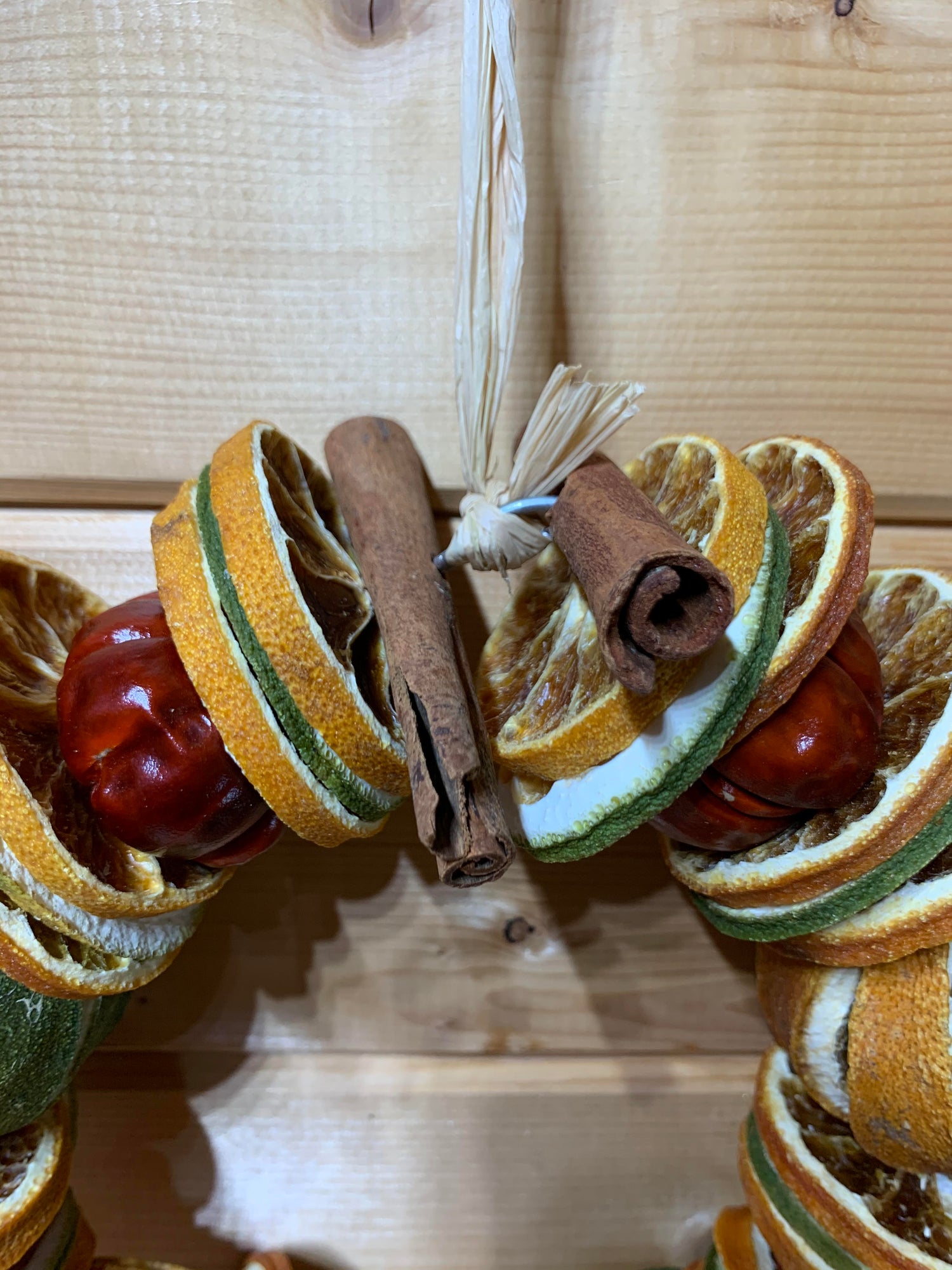 A gorgeous Christmas circle shaped wreath for your door made up of dried whole and sliced oranges and limes, small red peppers and cinnamon sticks on a wire base.