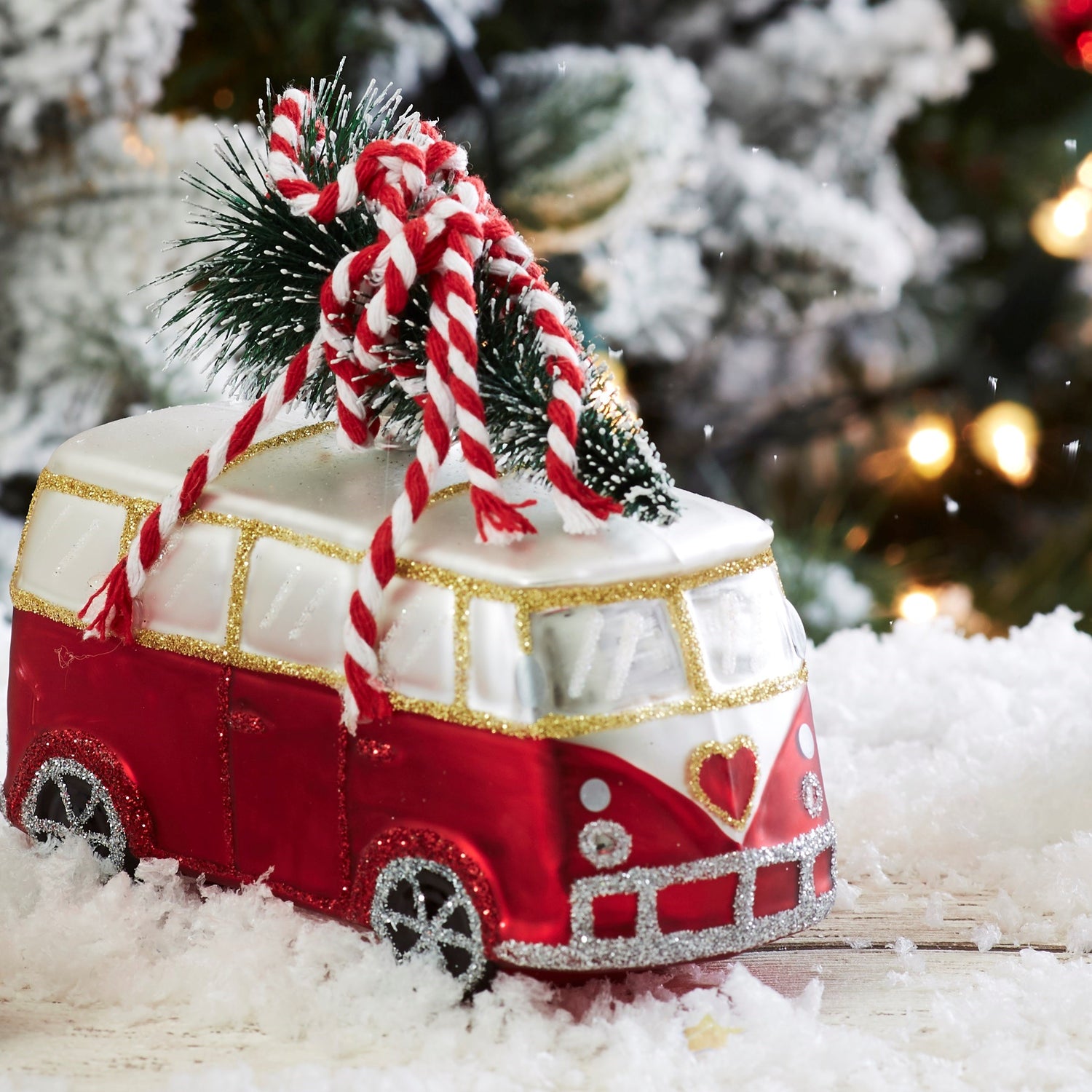 A very cool red and white camper van carrying a Christmas tree in the snow.