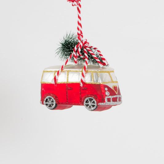 A very cool red and white camper van carrying a Christmas tree in the snow.