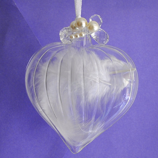 Clear love heart shaped glass hanging Christmas decoration with a white birds feather inside.