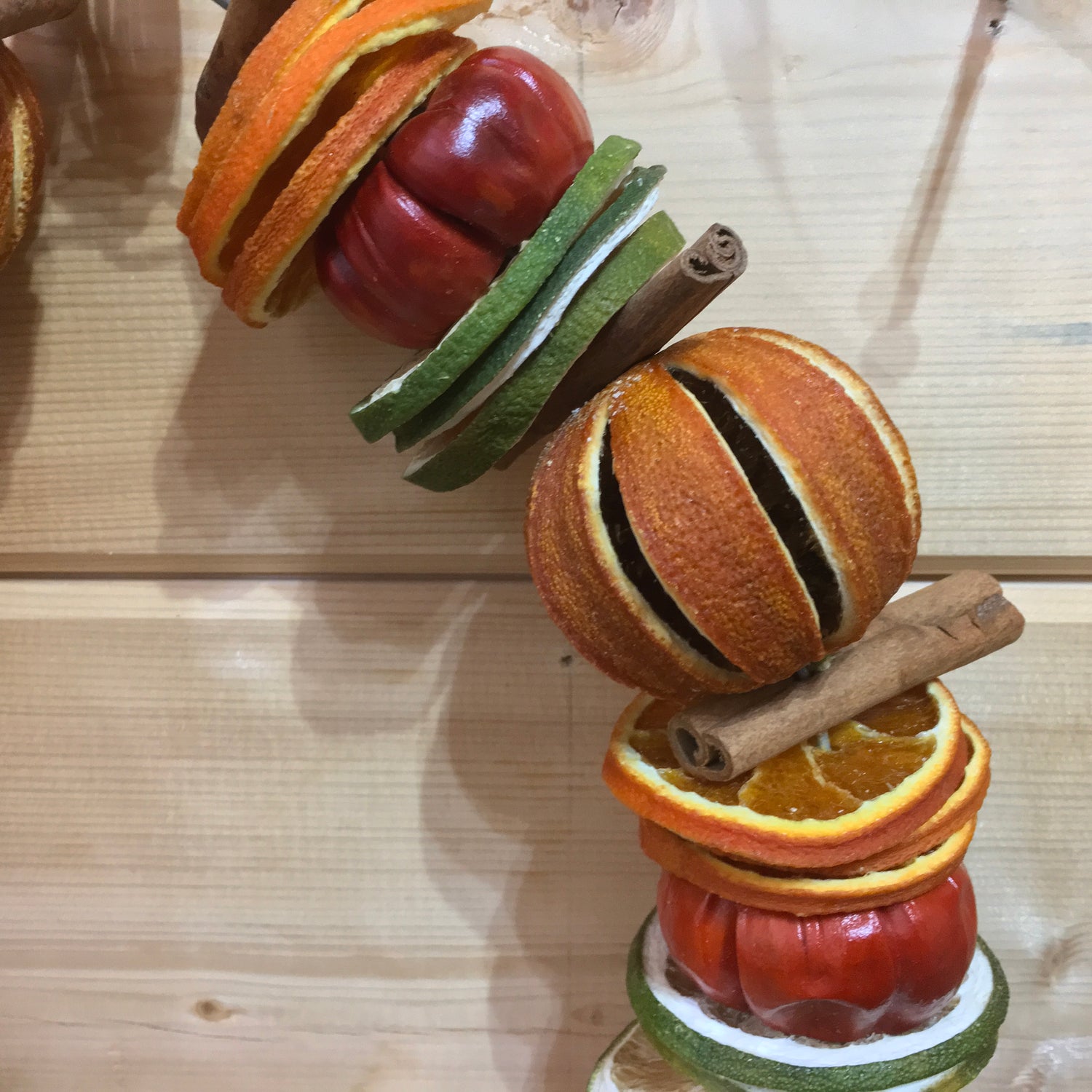 Hanging Christmas fruit circle decoration made from dried whole oranges and sliced limes with cinnamon sticks and small red peppers.