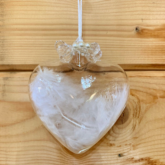 Clear love heart shaped glass hanging Christmas decoration with a white birds feather inside and pearls detail at the top of the heart.