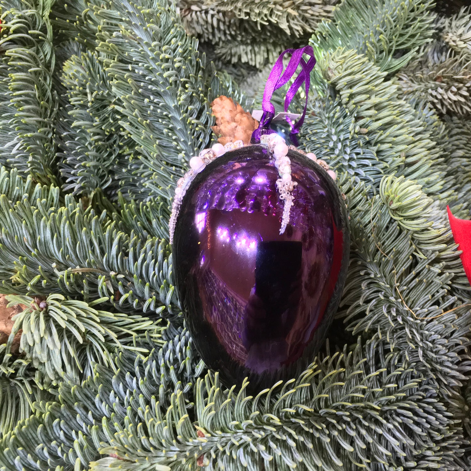 This shiny purple egg shape Christmas ornament is made from glass and decorated with beads, pearls and diamonte.
