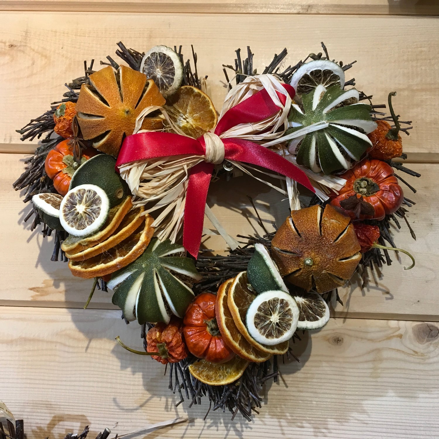 Heart shaped twig wreath that has been beautifully decorated with an assortment of dried fruits, and cinnamon sticks and scented with a wonderful Christmas fragrance. With an additional decorative red bow and hanger.