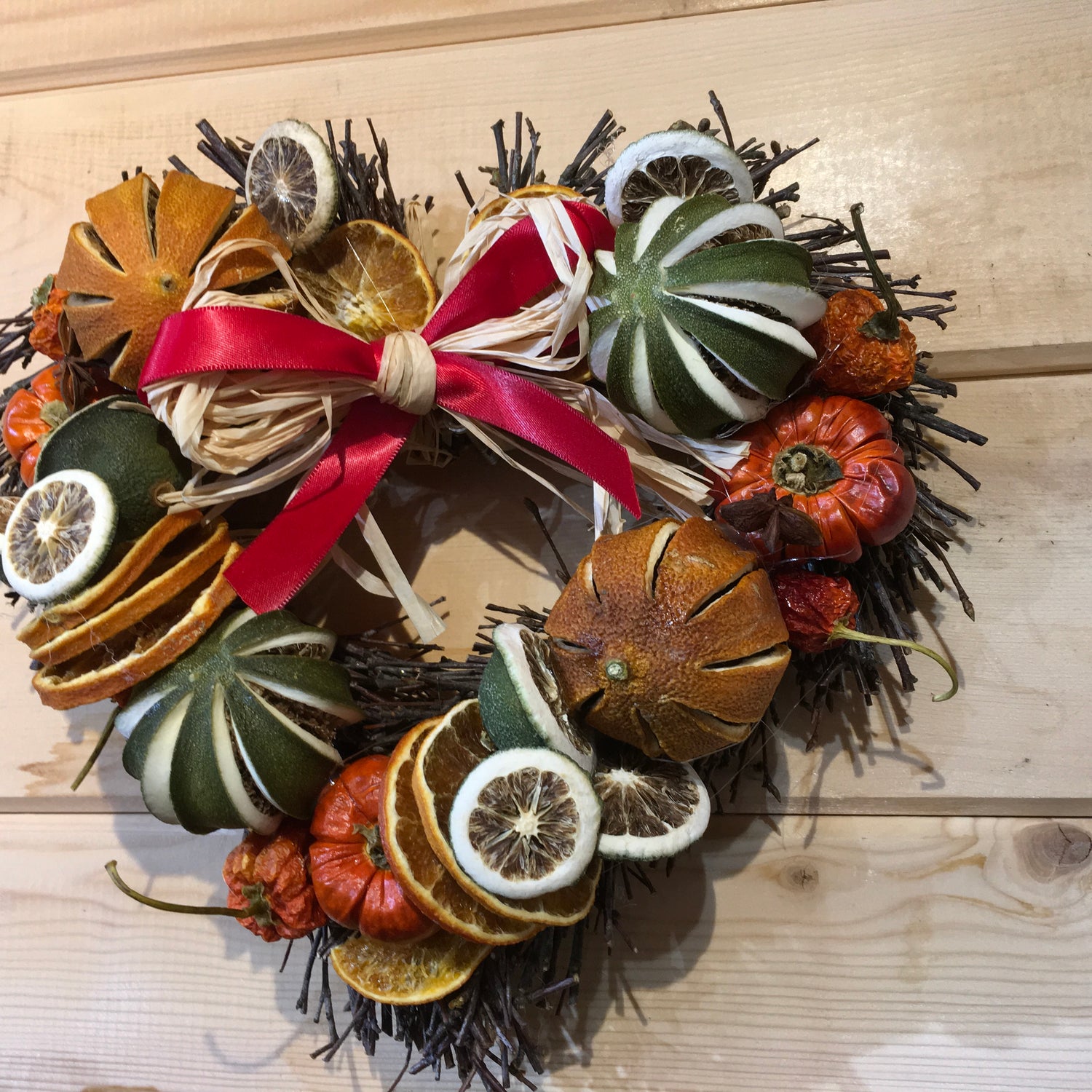 Heart shaped twig wreath that has been beautifully decorated with an assortment of dried fruits, and cinnamon sticks and scented with a wonderful Christmas fragrance. With an additional decorative red bow and hanger.