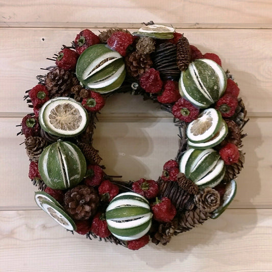 Christmas door wreath decorated with green limes and red peppers, white fir cones on a natural willow base.