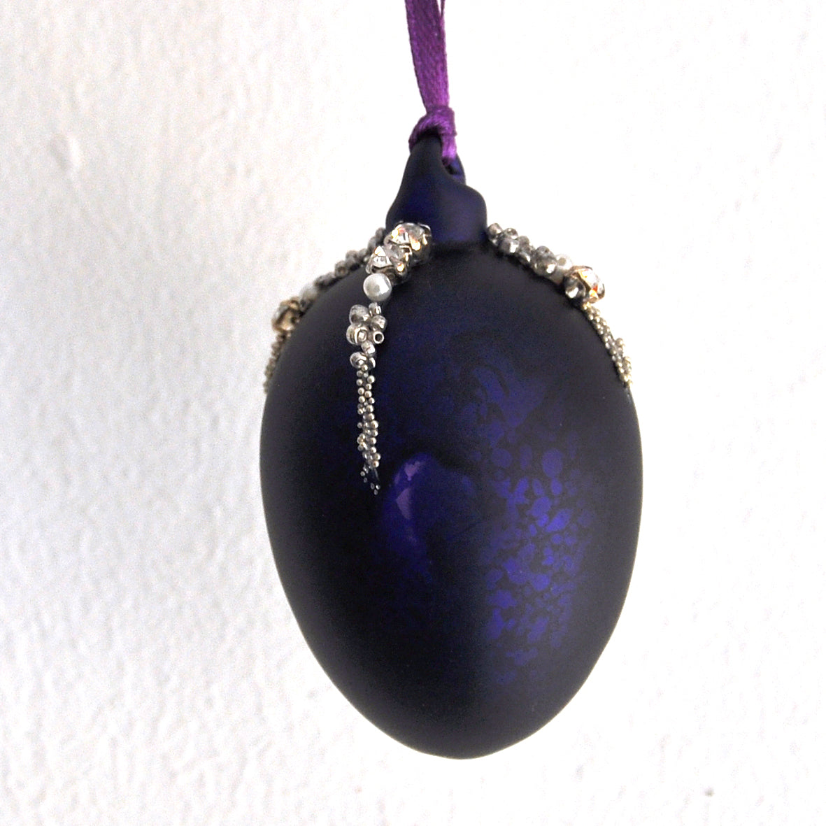 These matt aubergine purple egg shape Christmas ornament is made from glass and decorated with beads, pearls and diamonte.